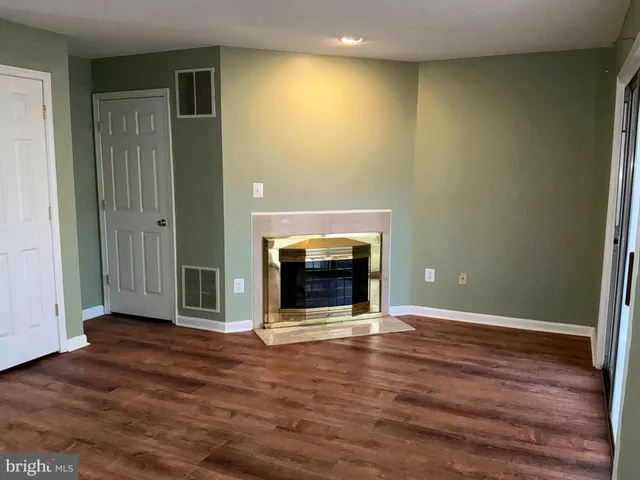 an empty room with wooden floor fireplace and window