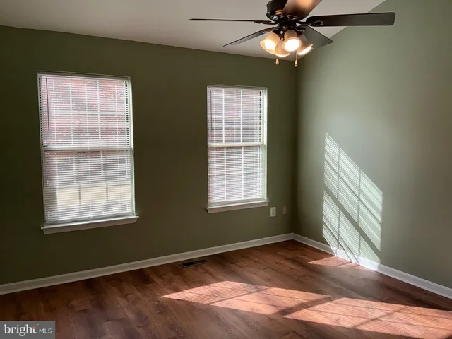 a view of an empty room with window and chandelier fan