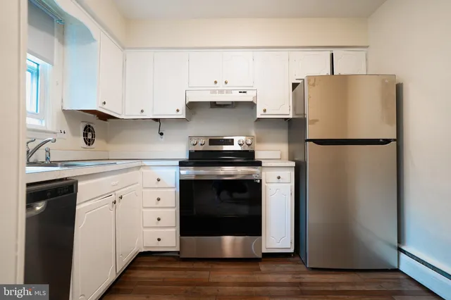 a kitchen with stainless steel appliances granite countertop white cabinets a sink a stove and dishwasher