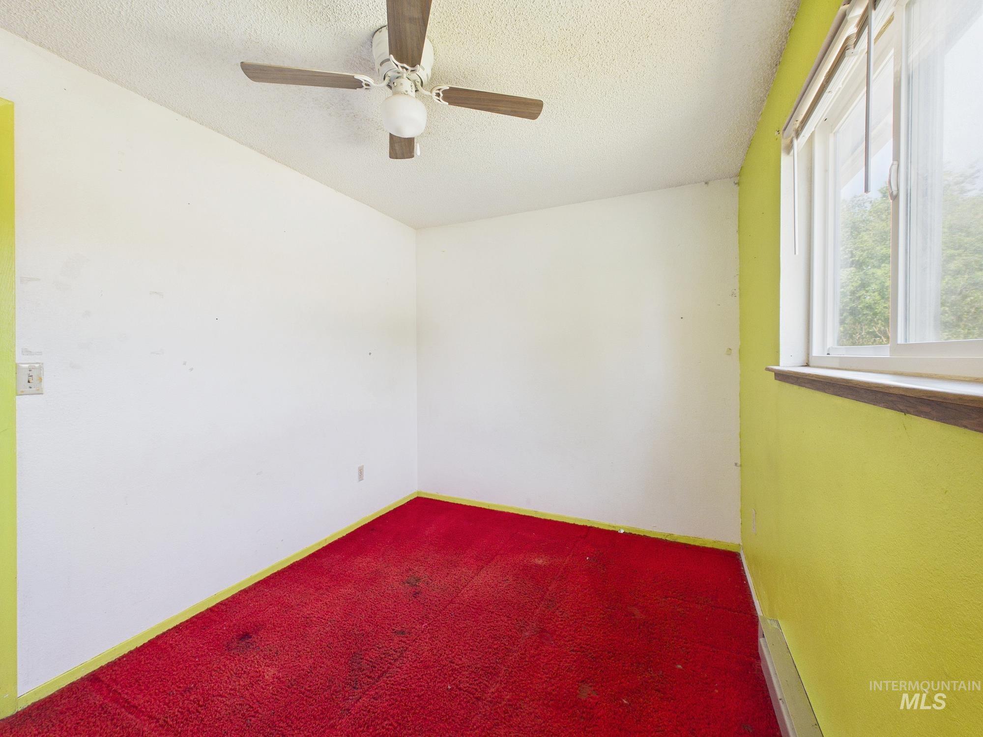 1527 North Plaza Road Emmett, ID 83617 - Photo 24 of 33 Room featuring a window with a wood sill, red carpeting, painted walls, and a ceiling fan with light fixture