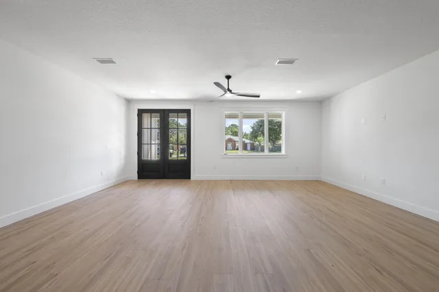 a view of an empty room with a window and wooden floor