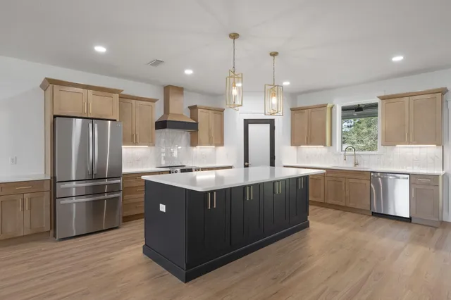 a kitchen with kitchen island a counter space a sink appliances and cabinets