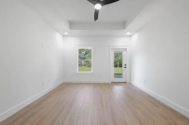 a view of an empty room with a window and wooden floor