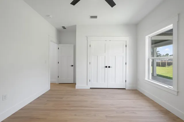 an empty room with a window and a ceiling fan