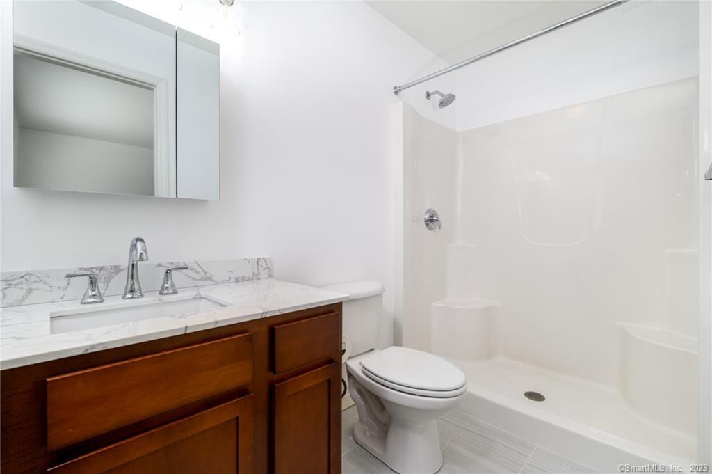 217 Highlawn Road Fairfield, CT 06824 - Photo 14 of 27 a bathroom with a granite countertop sink toilet a mirror and shower