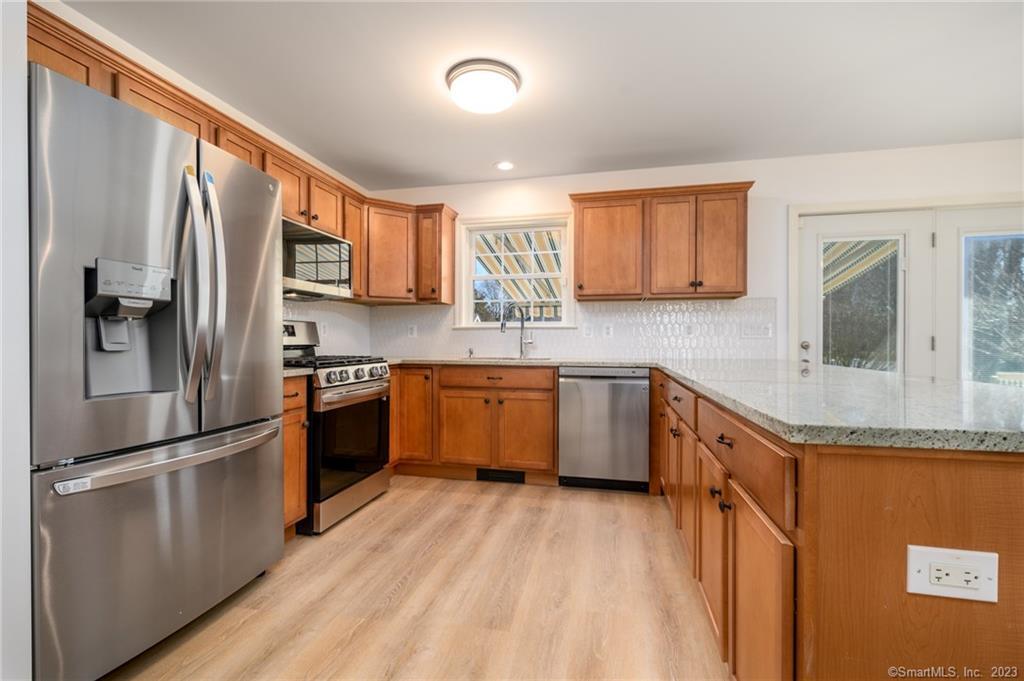 217 Highlawn Road Fairfield, CT 06824 - Photo 9 of 27 a kitchen with granite countertop a refrigerator oven a sink dishwasher and white cabinets with wooden floor