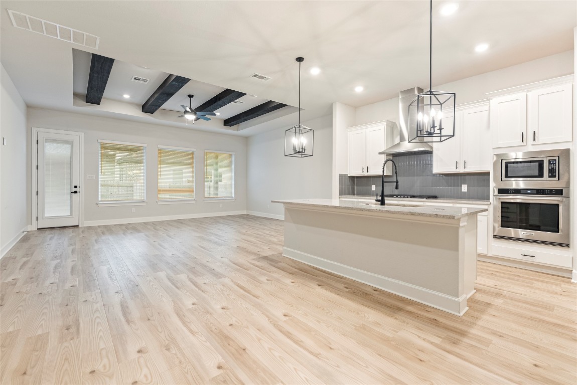 17113 Howdy Way Manor, TX 78653 - Photo 24 of 25 a large white kitchen with kitchen island a stove a sink dishwasher and a oven with wooden floor