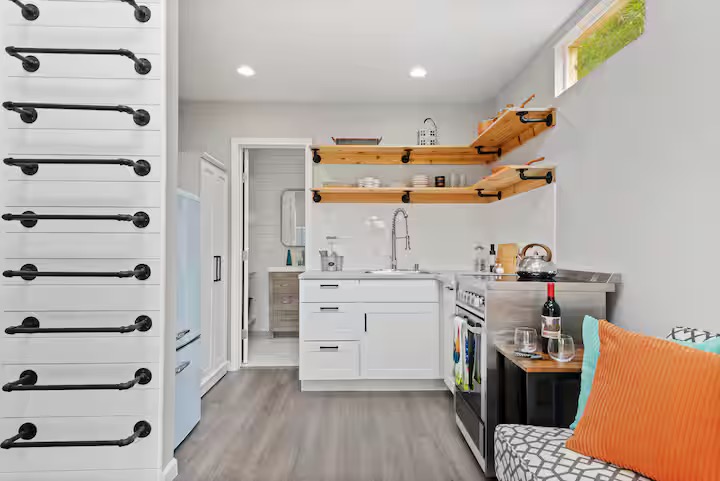 307 East 35th Street, Unit A Austin, TX 78705 - Photo 31 of 40 A compact kitchen boasts streamlined white cabinetry, stainless steel appliances, and sleek open shelving, perfect for modern living.
