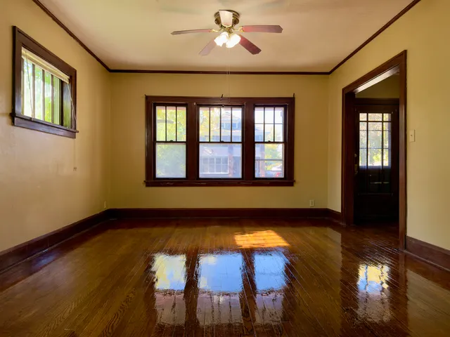a view of an empty room with window and wooden floor