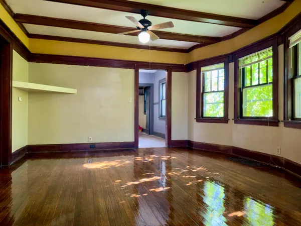 a view of empty room with wooden floor and fan