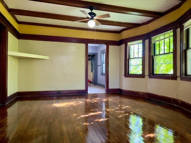 a view of empty room with wooden floor and fan
