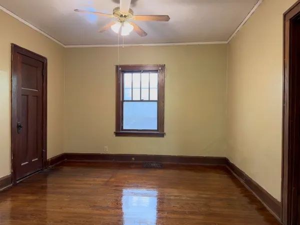 an empty room with wooden floor and fan