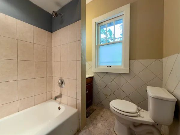 a white toilet sitting next to a bath tub and a shower