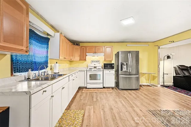 a large kitchen with a stove a sink dishwasher a refrigerator with wooden cabinets and floor