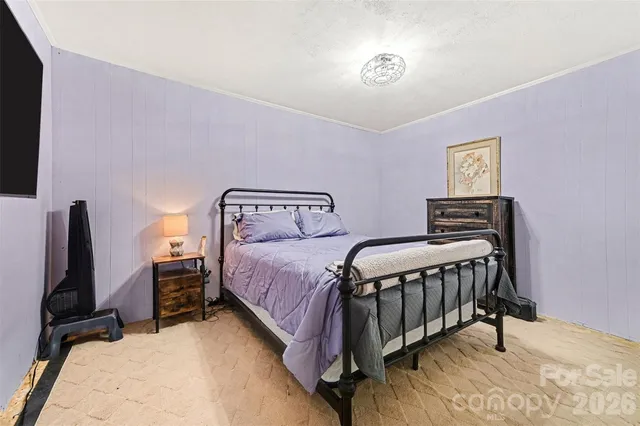 a bedroom with a bed and a flat tv screen on a dresser