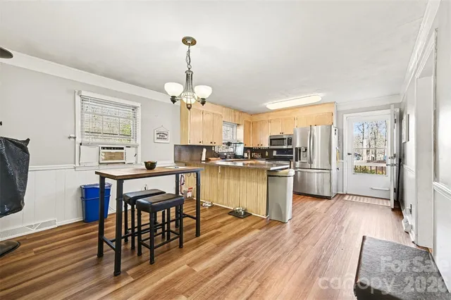 a kitchen with a refrigerator a microwave oven a stove and a dining table with wooden floor