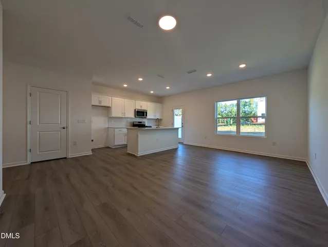 a view of an empty room with window and wooden floor