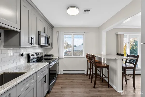 a kitchen with stainless steel appliances granite countertop a stove a sink a microwave cabinets and a dining table