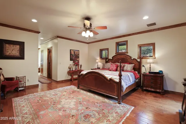 a bedroom with a bed ceiling fan and a wooden floor