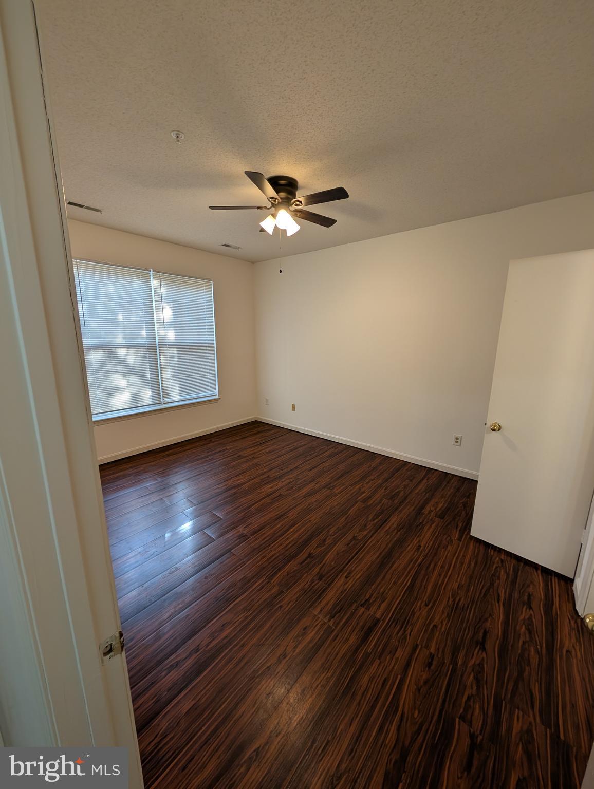 7115 Sandown Circle, Unit 202 Windsor Mill, MD 21244 - Photo 51 of 60 an empty room with wooden floor chandelier fan and windows