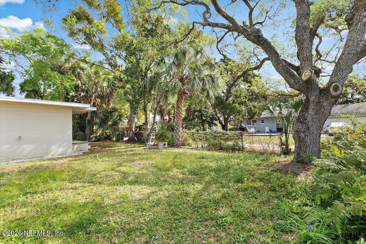 103 Coronado Street St. Augustine, FL 32080 - Photo 24 of 25 a backyard of a house with large trees and a wooden fence