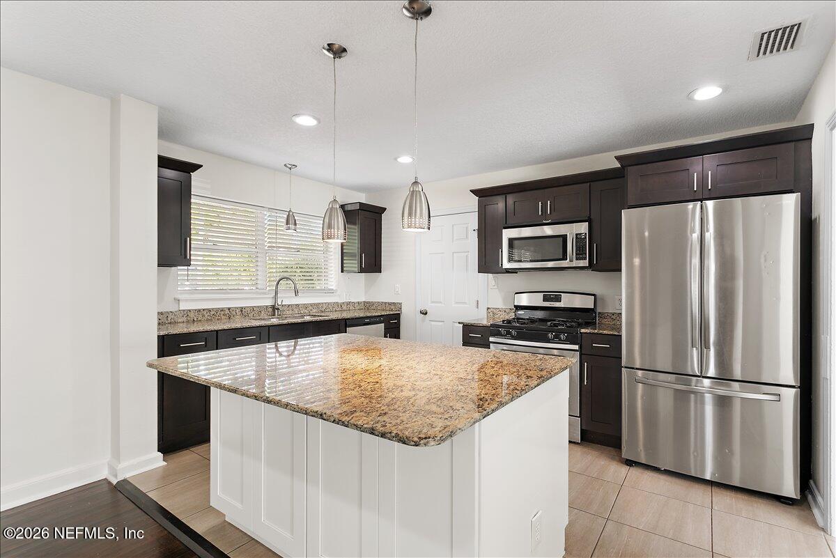 103 Coronado Street St. Augustine, FL 32080 - Photo 6 of 25 a kitchen with stainless steel appliances granite countertop a sink stove and refrigerator