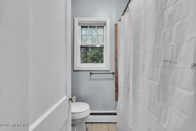 a bathroom with a sink a toilet a window and shower