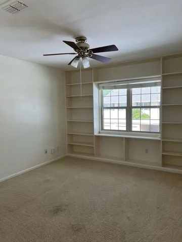 an empty room with a ceiling fan and window