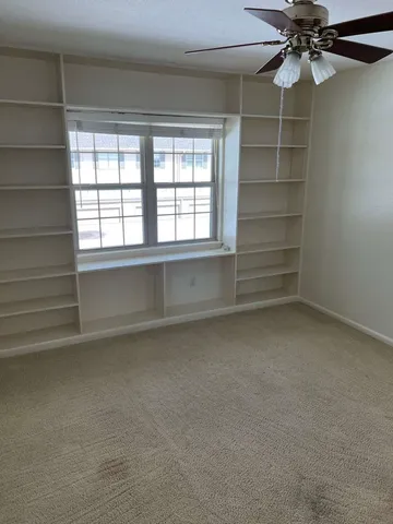 an empty room with a windows and chandelier fan