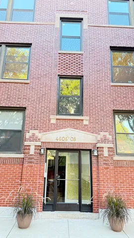 a front view of a building with a garden and plants