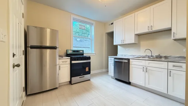 a kitchen with stainless steel appliances granite countertop a refrigerator sink and stove