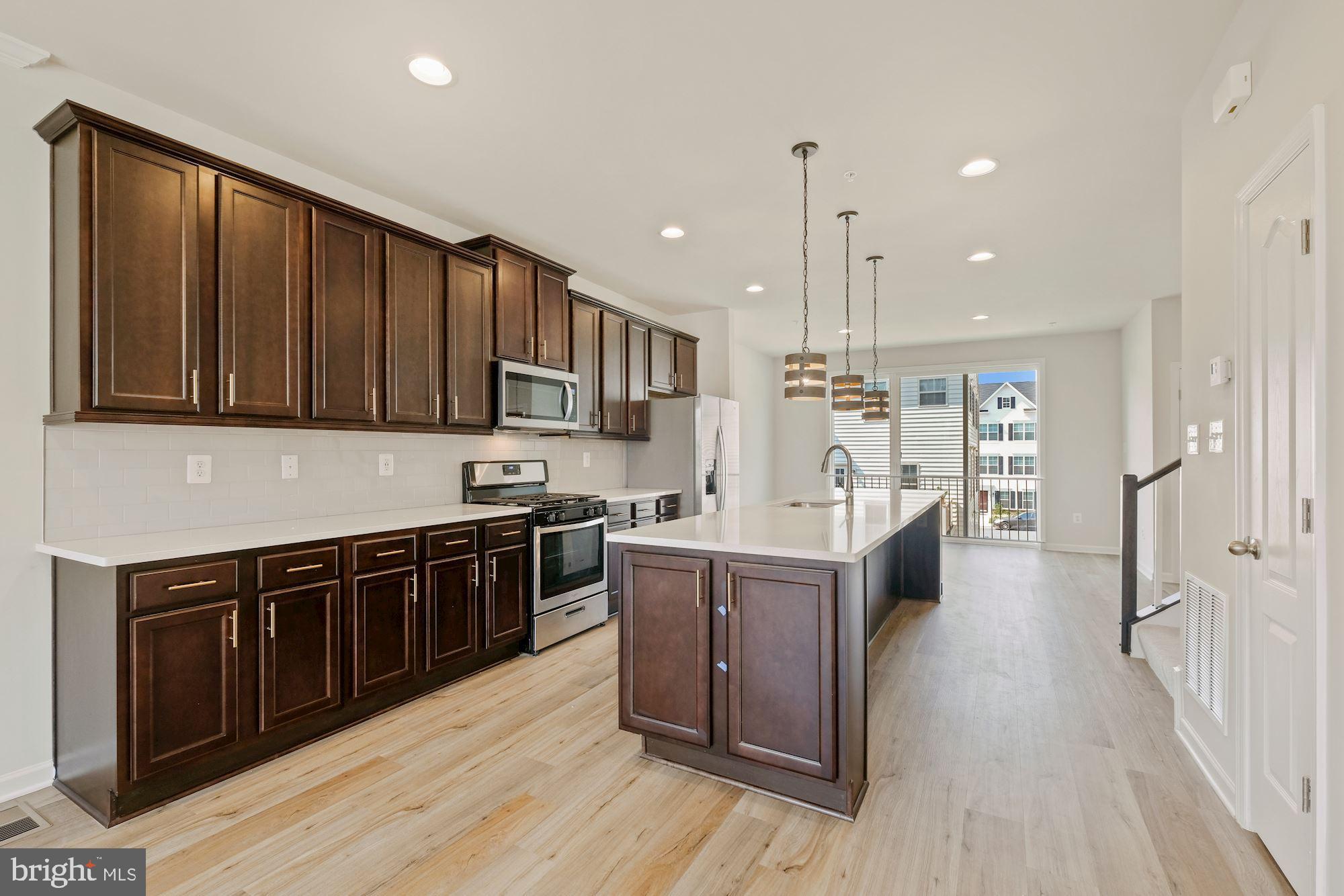 6211 Davinci Street Frederick, MD 21703 - Photo 7 of 30 a kitchen with stainless steel appliances granite countertop a stove top oven a sink dishwasher and a refrigerator with wooden floor