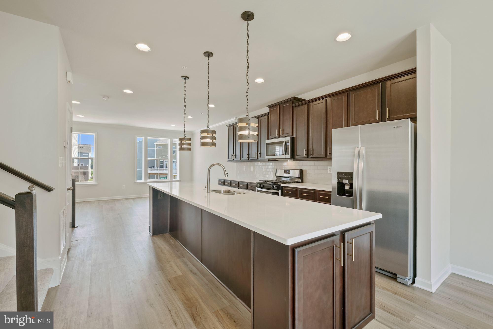 6211 Davinci Street Frederick, MD 21703 - Photo 10 of 30 a kitchen with kitchen island a sink a stove a refrigerator and wooden floor