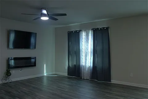 an empty room with wooden floor a ceiling fan and a window