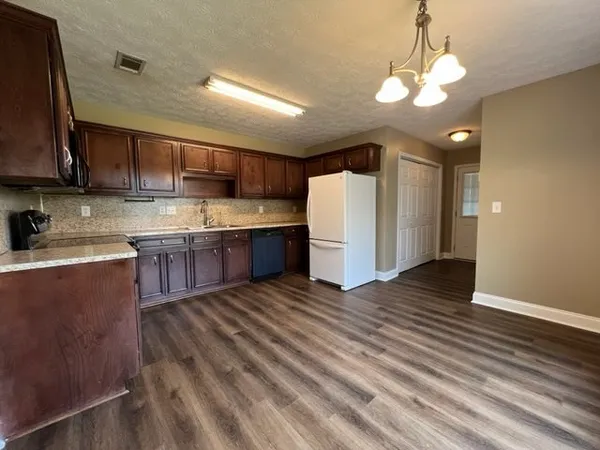 a kitchen with stainless steel appliances granite countertop a sink a stove a refrigerator cabinets and wooden floor