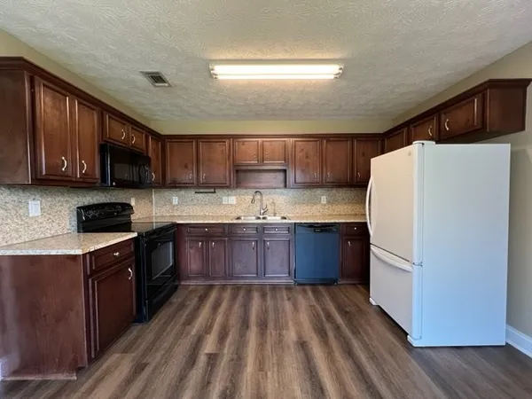 a kitchen with stainless steel appliances granite countertop wooden cabinets a refrigerator a sink and a stove