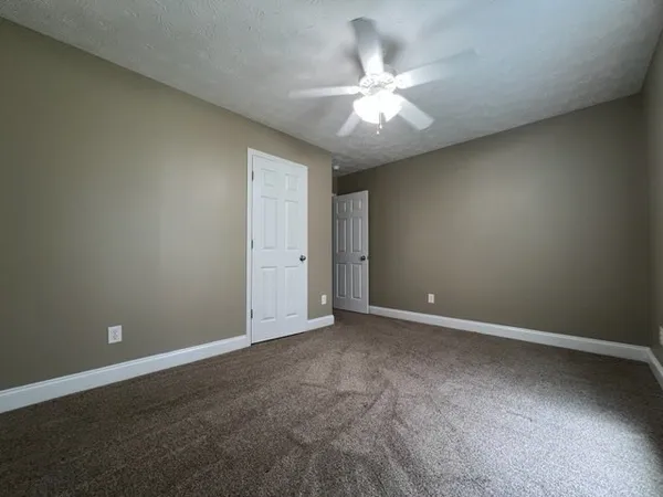 an empty room with a chandelier fan and windows