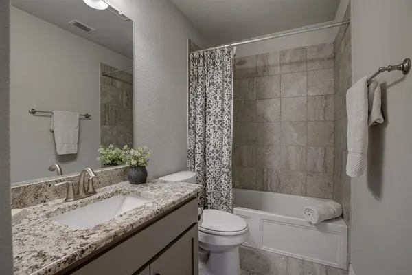 a bathroom with a granite countertop sink toilet mirror and shower