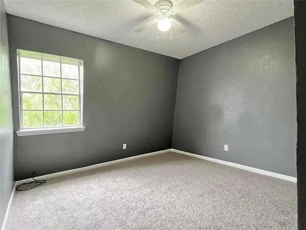 an empty room with windows and fan