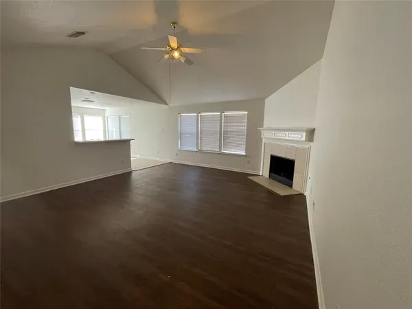 an empty room with wooden floor fan and windows