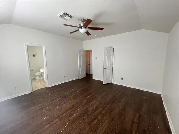 an empty room with wooden floor a ceiling fan and windows
