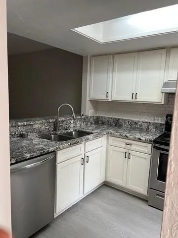 a kitchen with granite countertop white cabinets and a sink