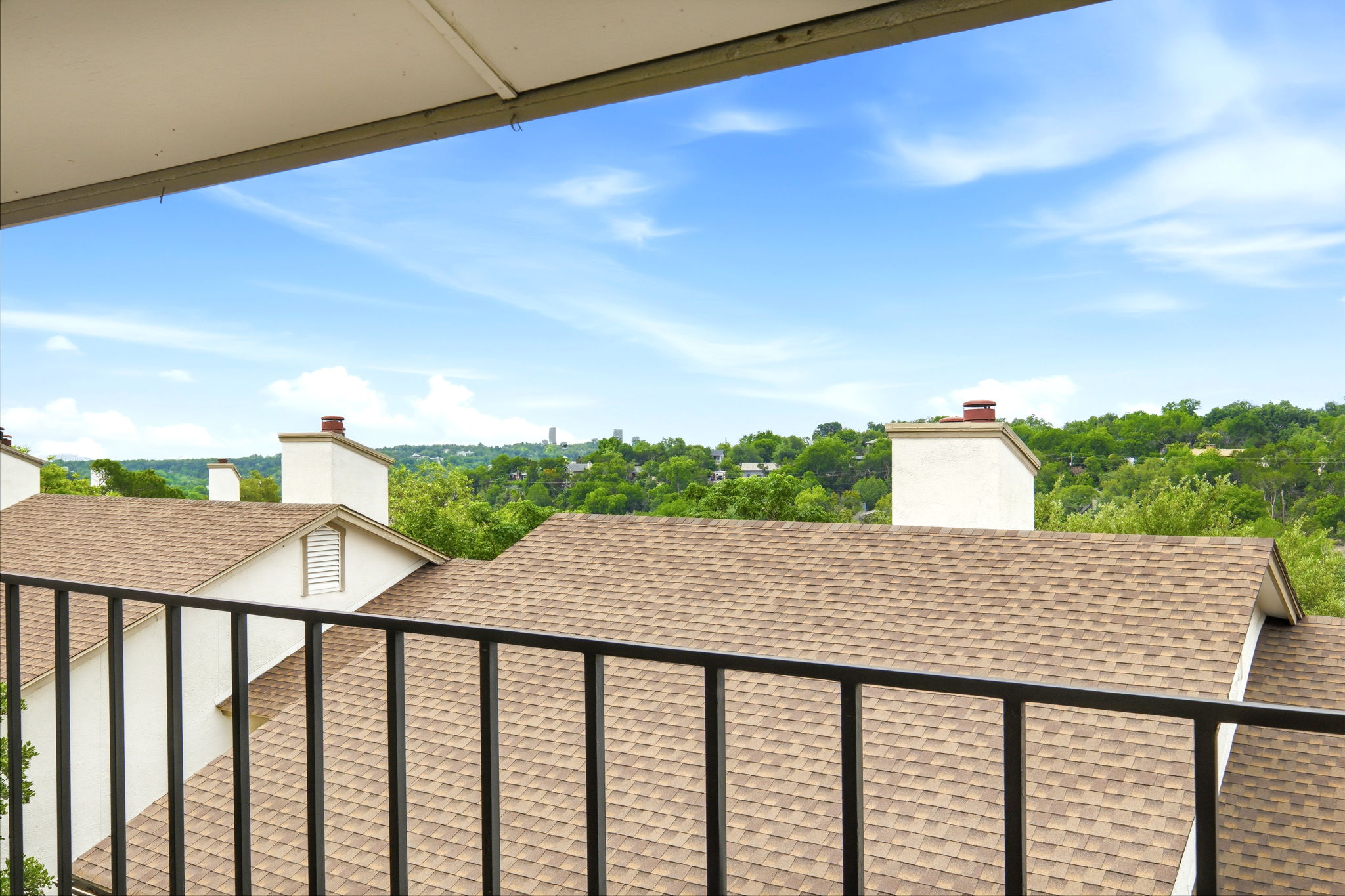 6910 Hart Lane, Unit 912 Austin, TX 78731 - Photo 3 of 36 Balcony presenting a panoramic landscape featuring a clear sky, distant green hills, and residential rooftops with shingle material