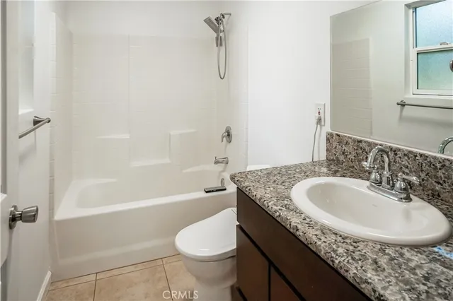 a bathroom with a granite countertop sink a toilet a mirror and bathtub