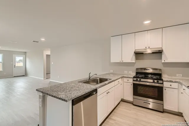 a kitchen with granite countertop a sink stove and cabinets