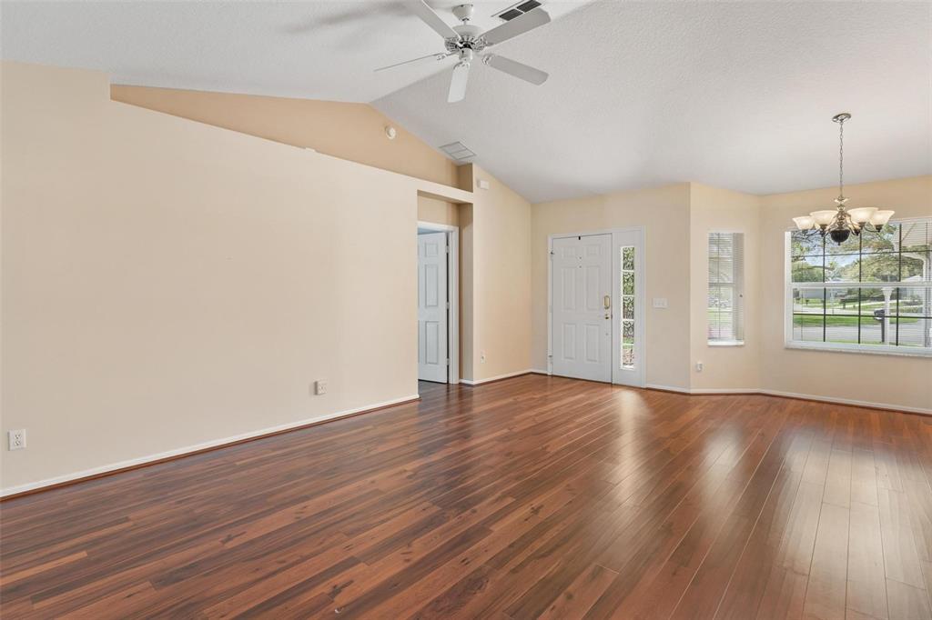 11614 Southeast 172nd Loop Summerfield, FL 34491 - Photo 8 of 55 an empty room with wooden floor chandelier fan and windows