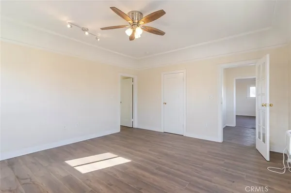 an empty room with wooden floor and a ceiling fan