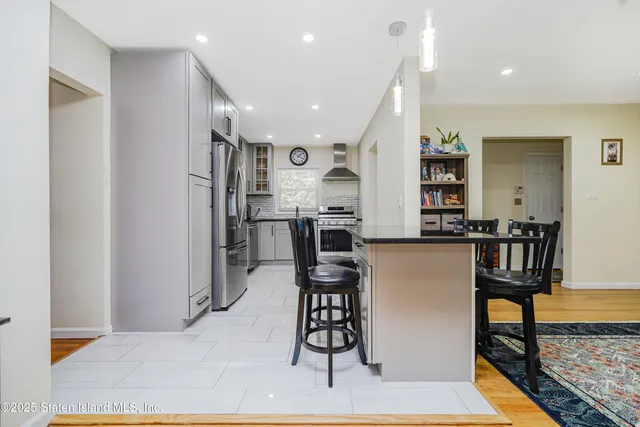 a kitchen with stainless steel appliances kitchen island granite countertop refrigerator and cabinets