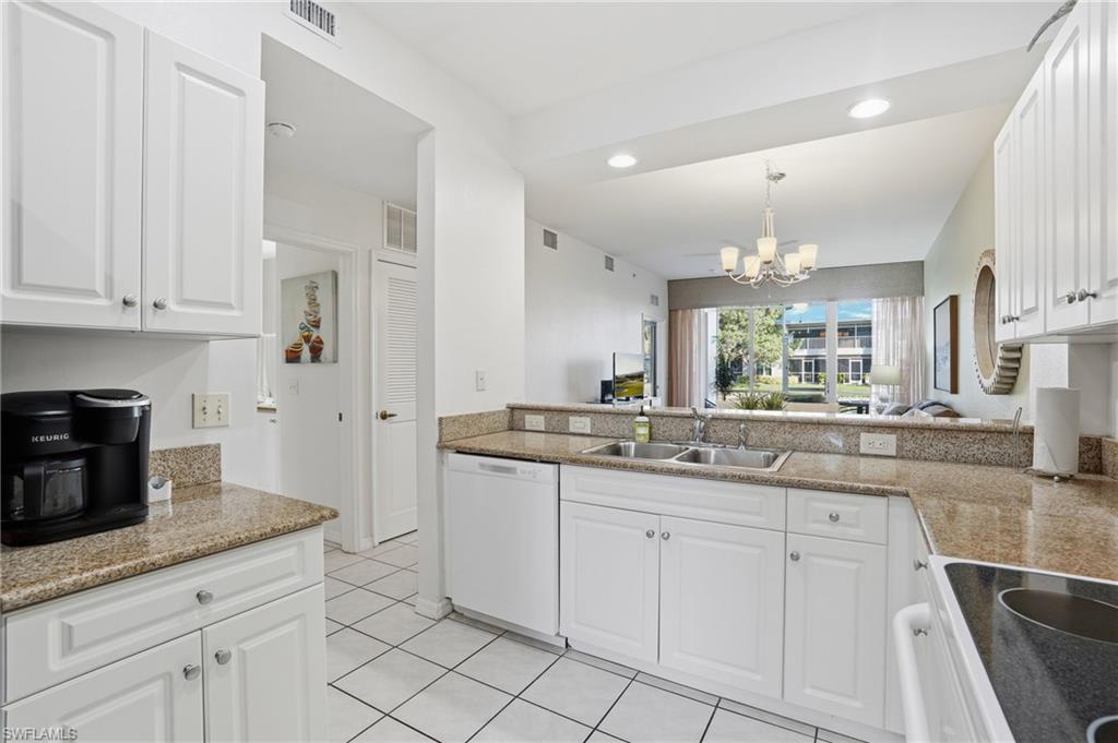 7920 Mahogany Run Lane, Unit 1015 Naples, FL 34113 - Photo 15 of 41 a kitchen with white cabinets and chandelier