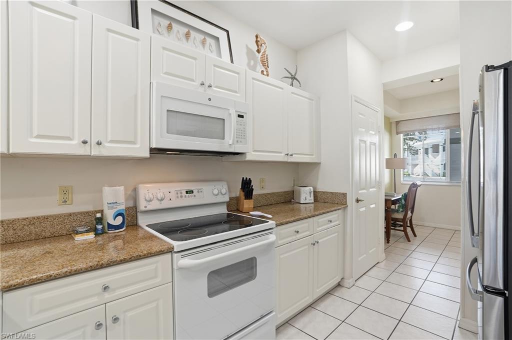 7920 Mahogany Run Lane, Unit 1015 Naples, FL 34113 - Photo 16 of 41 a kitchen with granite countertop white cabinets stainless steel appliances and sink